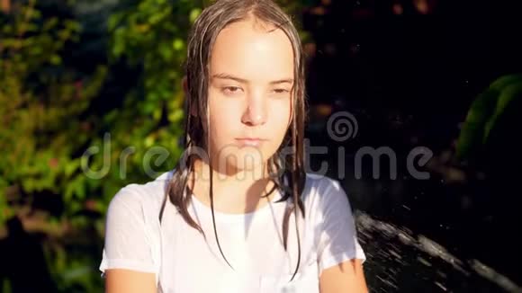 少女面对花园时从花园水管泼水的慢镜头视频的预览图
