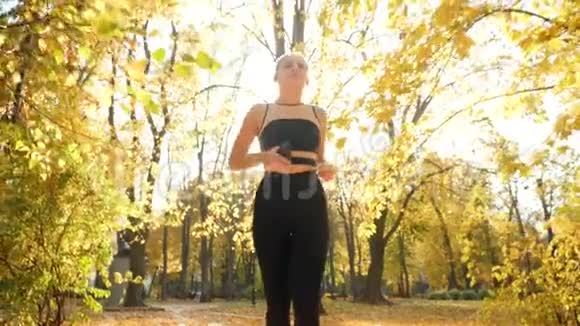 从低处看美丽的少女在树下长长的小巷里奔跑秋天公园里有金色的叶子视频的预览图