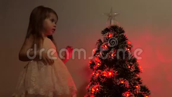 孩子在节日树上检查一颗圣诞星小女孩在儿童房的圣诞树附近玩耍视频的预览图