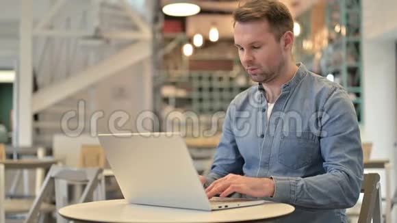 在咖啡馆里用笔记本电脑时头痛的休闲男士视频的预览图