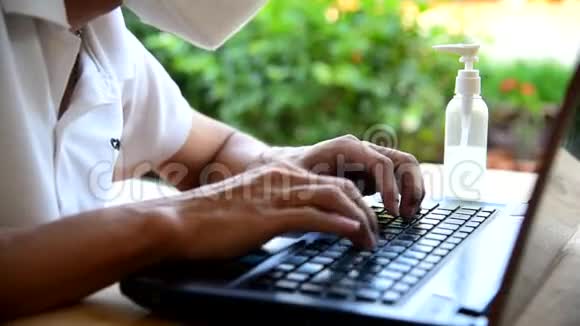 这名男子戴着N95面罩在家工作时使用笔记本电脑视频的预览图