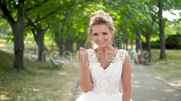 4k视频快乐微笑的年轻新娘走在公园的长巷子里对着镜头微笑视频的预览图