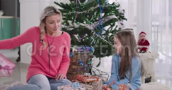年轻的高加索美女送给可爱的女孩圣诞礼物母亲和女儿庆祝新年前夜视频的预览图
