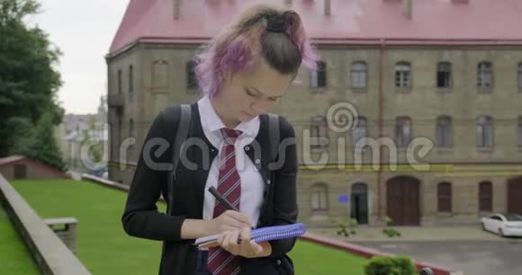穿着校服的少女背着背包写作展示单词开始视频的预览图