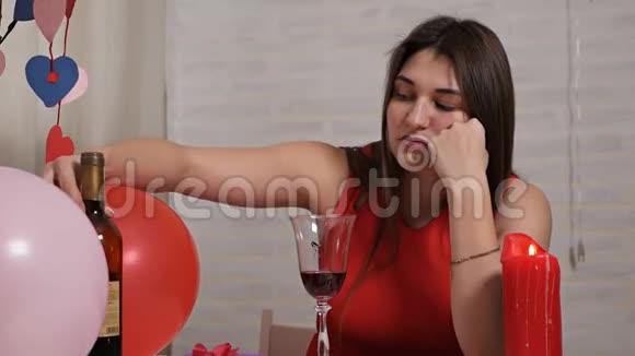 一个穿着红色裙子的漂亮女孩独自在餐桌上喝着一杯酒同时陶醉孤独的情人视频的预览图