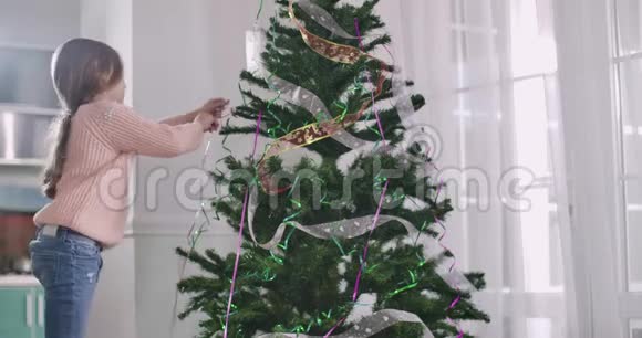 布鲁内特高加索女孩用花环装饰圣诞树新年前夕为圣诞做准备孩子视频的预览图
