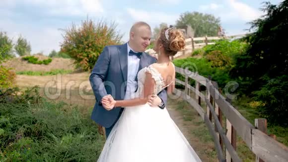 一对新婚夫妇在乡下的长木栅栏旁跳舞接吻的慢动作视频视频的预览图
