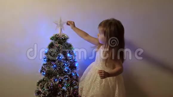 孩子在节日树上检查一颗圣诞星小女孩在孩子们的房间里靠近圣诞树玩耍视频的预览图