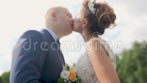 婚礼后阳光明媚的一天美丽的新婚夫妇在花园里接吻的4K特写视频视频的预览图