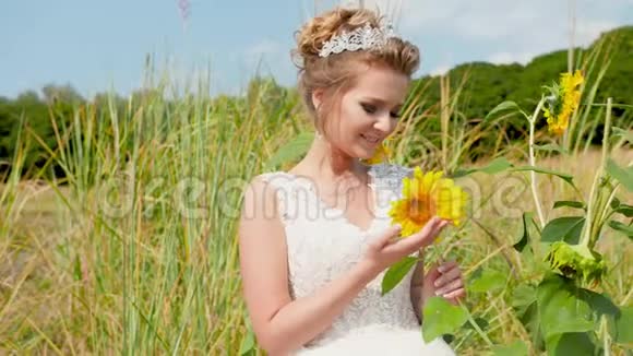 特写4k视频美丽的微笑新娘抱着黄色的向日葵在阳光明媚的夏日在田野里摆姿势视频的预览图