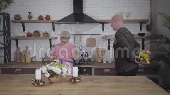 开朗成熟的白种人秃顶男人把一束黄色郁金香送给他可爱的妻子穿粉色衣服的白种人视频的预览图