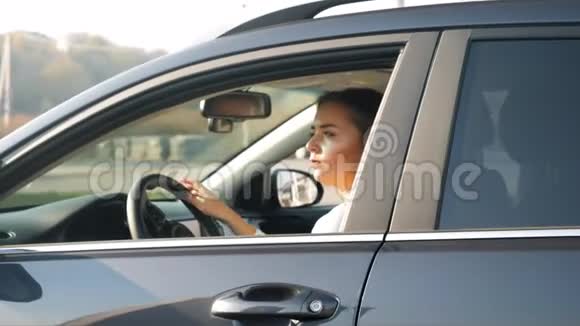 年轻漂亮的女司机在购物中心的停车场上开汽车时的慢动作视频视频的预览图