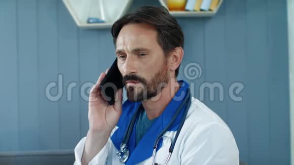 关闭疲惫的男医生在办公室里打电话医生听力病人视频的预览图