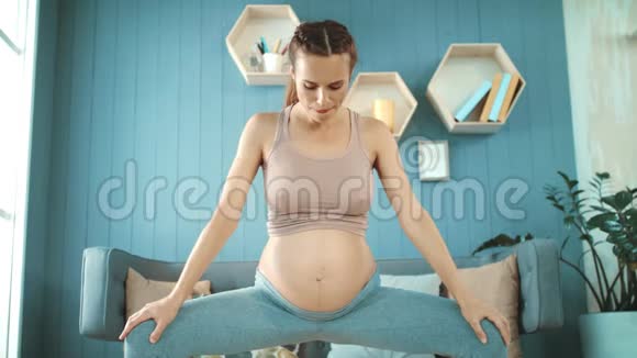 微笑着怀孕的肚子妈妈在家做呼吸运动视频的预览图