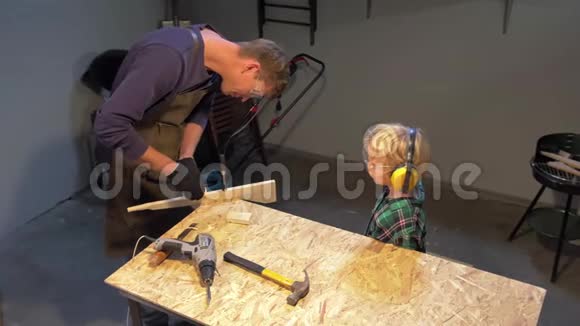 男孩看工匠如何制造木制产品慢动作视频的预览图