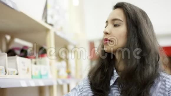 年轻女子在超市拿食物学习包装上的信息把它加到购物篮里视频的预览图