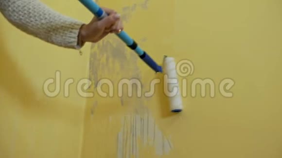 一个自学的女孩准备一堵墙用一个建筑滚筒画画一个女孩在工作她处理黄色的墙视频的预览图