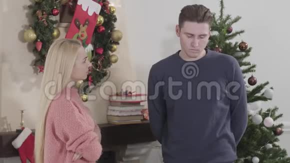 愤怒的年轻女子冲着丈夫或男友大喊大叫除夕夜在圣诞树前吵架的夫妇视频的预览图