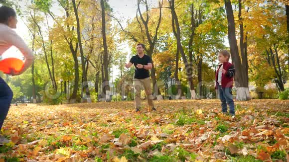 母亲父亲和小儿子在公园玩耍的4K视频秋天森林里的家庭玩飞盘视频的预览图