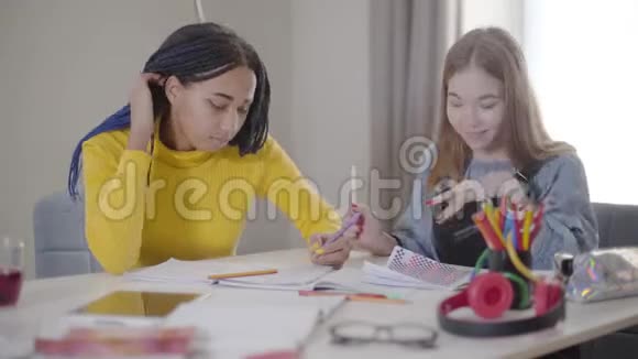 积极的白种人女孩拿着朋友的钢笔微笑在室内学习的年轻学生生活方式教育学习视频的预览图