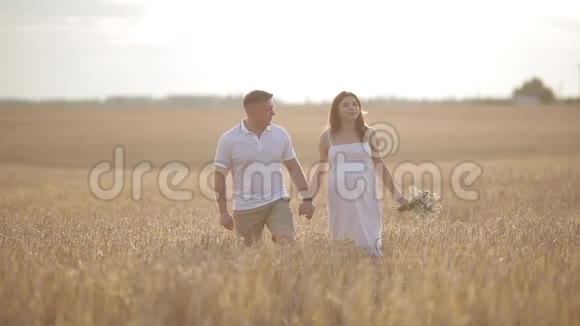 一对相爱的夫妇走在金色黑麦的田野里视频的预览图