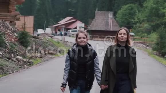 美丽的年轻母亲和女儿走在农村的道路上视频的预览图