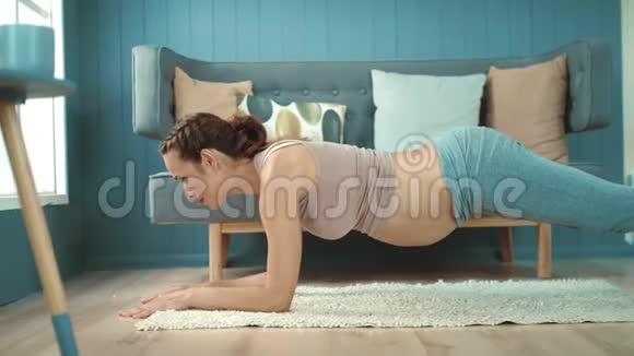 特写孕肚妈妈在轻客厅练习瑜伽木板姿势视频的预览图