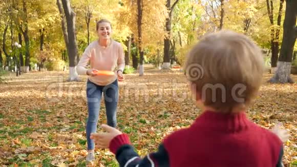 4k慢动作视频年轻的笑妈妈在秋天公园和小儿子玩飞盘视频的预览图