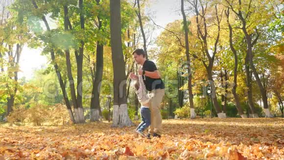 4K慢动作视频快乐的年轻父亲在秋天公园玩耍把他的小儿子扔到空中视频的预览图
