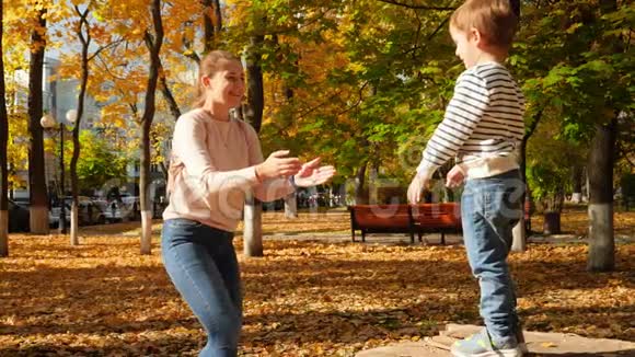 慢镜头视频快乐的微笑和笑的小男孩从树桩跳到他的母亲拥抱她在里面视频的预览图