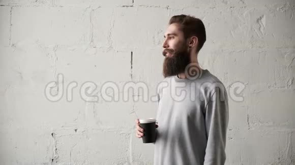 一个留着胡子的年轻人在窗外喝咖啡休息期间快乐程序员视频的预览图