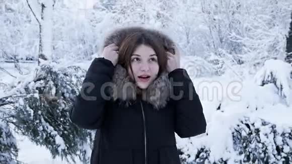 一个美丽的女孩在冬天的公园里心情愉快在雪地里欢乐的肖像视频的预览图