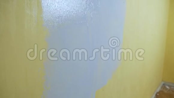 快乐的自学女孩用一个建筑滚筒画一堵黄色的墙和灰色的油漆独立公寓维修视频的预览图