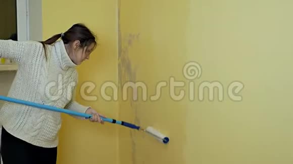 一个自学的女孩准备一堵墙用一个建筑滚筒画画一个女孩在工作她处理黄色的墙视频的预览图