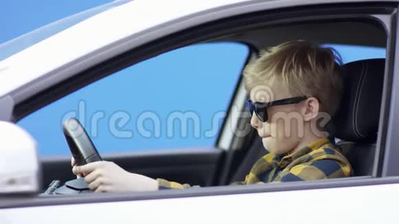一个穿休闲服装的金发小男孩正在旅行英俊的男孩正在驾驶绿色屏幕背景的汽车他是视频的预览图
