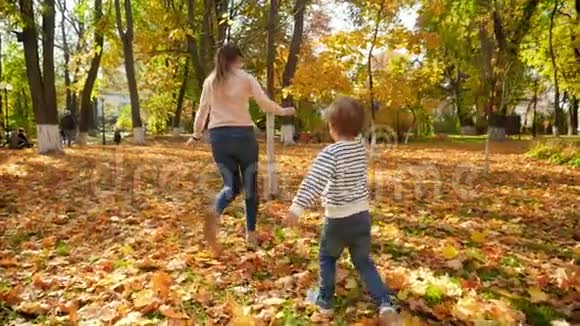小男孩在秋天公园玩耍和追赶妈妈的慢动作视频视频的预览图