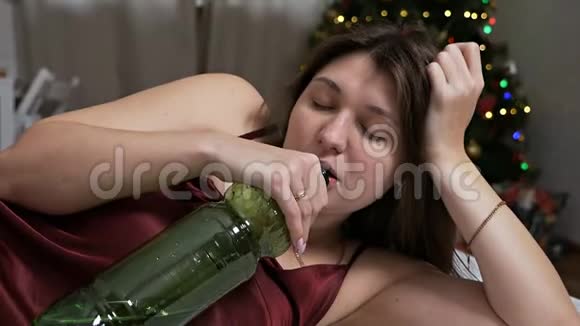 醉酒的女人在床上喝一杯水背景是圣诞树后的聚会概念是一个视频的预览图