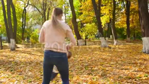4k视频快乐的年轻妈妈手牵着小儿子在秋天的公园里旋转视频的预览图