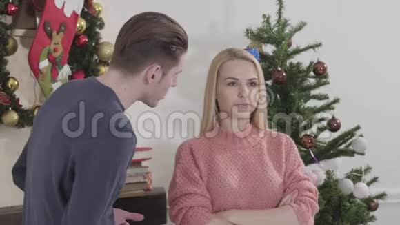 从侧面看成年白人男子在圣诞树前对漂亮女人大喊大叫一对夫妇在除夕争吵视频的预览图