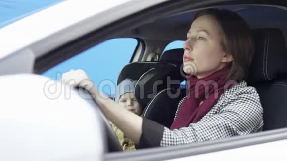 穿着便装的布鲁内特女士正在驾驶绿色屏幕背景的汽车她和儿子坐在车里视频的预览图