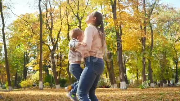 4k视频快乐微笑的母亲举起抛空旋转她的孩子在秋天公园视频的预览图