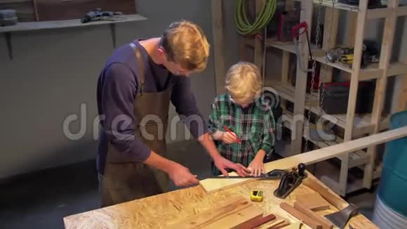 男人和男孩在车间里用木板工作视频的预览图