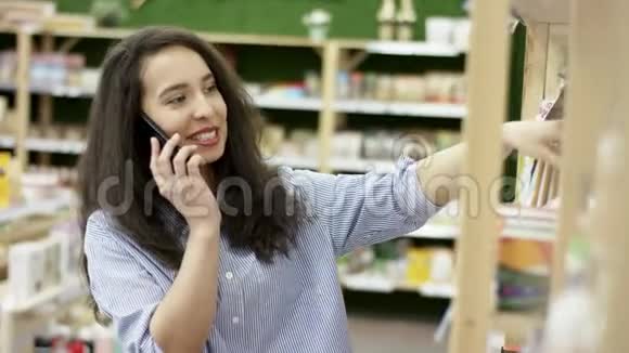 在运动营养店逛市场选货打电话的女孩视频的预览图