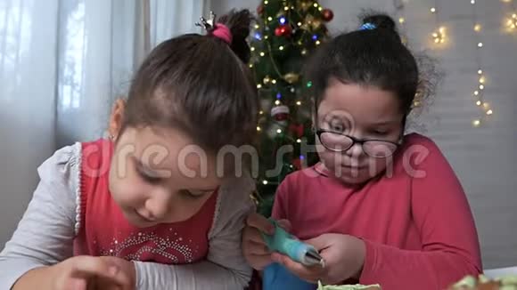 小孩子在圣诞树的背景上用奶油装饰圣诞姜饼饼干圣诞节视频的预览图