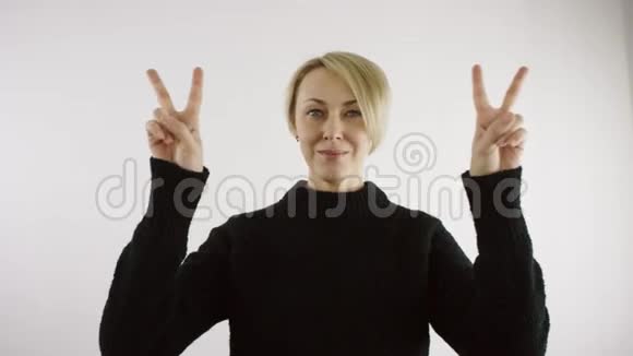 成年白种人金发短毛的白种人正在用两只手的手指做胜利的手势视频的预览图