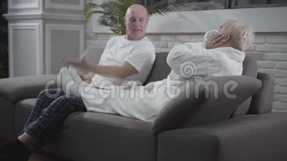 坐在沙发上按摩妻子脚的白人老人的画像丈夫照顾他可爱的配偶视频的预览图