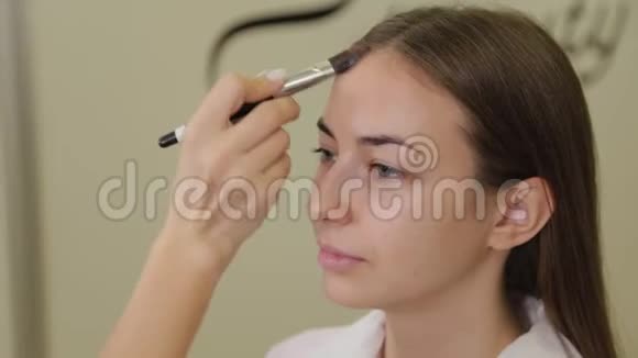 专业化妆师用刷子将粉底霜涂在客户的脸上视频的预览图