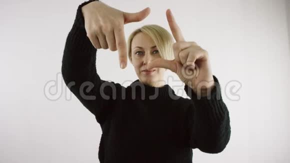 成年白种人金发短毛的白种人女人正用手指在明亮的白色背景下做框架视频的预览图