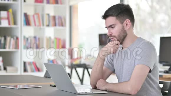 体贴的年轻人在办公室里用笔记本电脑视频的预览图