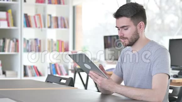 一位严肃的年轻人在办公室里用数码平板电脑视频的预览图